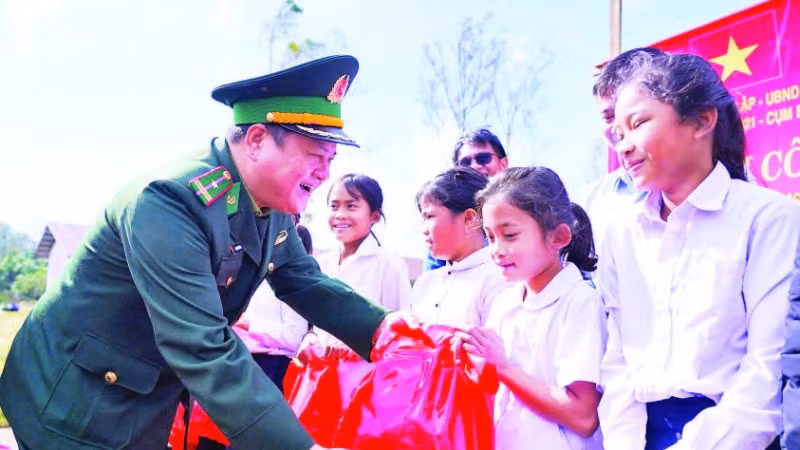 Cán bộ Đồn Biên phòng Hướng Lập trao quà tặng học sinh hai bên biên giới.