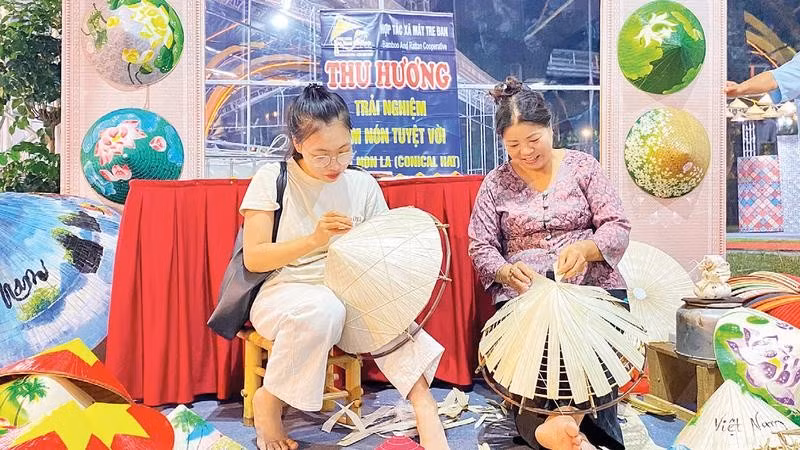 Khách trải nghiệm chằm nón tại gian hàng Hợp tác xã Mây tre nón lá Thu Hương, xã Thanh Oai.