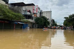 Ngập úng tại khu vực ngã tư san nền, phường Phan Đình Phùng. Phía xa là lực lượng chức năng, người dân tập trung hỗ trợ các thuyền đón người từ vùng ngập ra. (Ảnh: TUẤN SƠN).