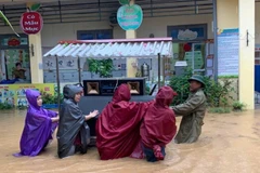 Giáo viên và lực lượng tại chỗ di chuyển đồ dùng học tập ra khỏi vùng ngập tại trường Tiểu học Sông Cầu. (Ảnh: KHÁNH LINH)