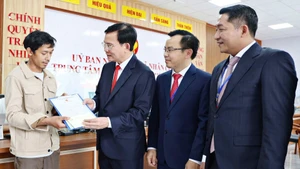Chủ tịch UBND tỉnh Lâm Đồng Hồ Văn Mười tặng quà một người dân làm thủ tục đăng ký khai sinh cho con tại Trung tâm Phục vụ hành chính công xã Nhân Cơ