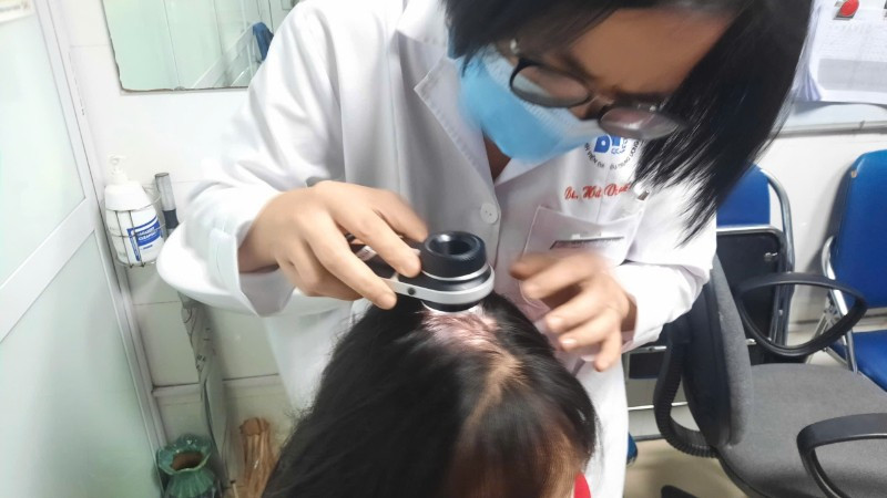 Bác sĩ kiểm tra tình trạng rụng tóc của bệnh nhân.