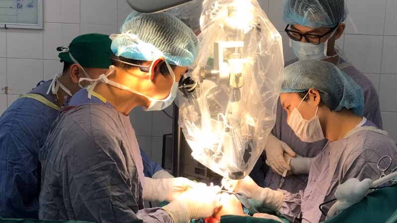 Ê-kíp mổ thực hiện vi phẫu nối lại ngón tay cho người bệnh với kính hiển vi.