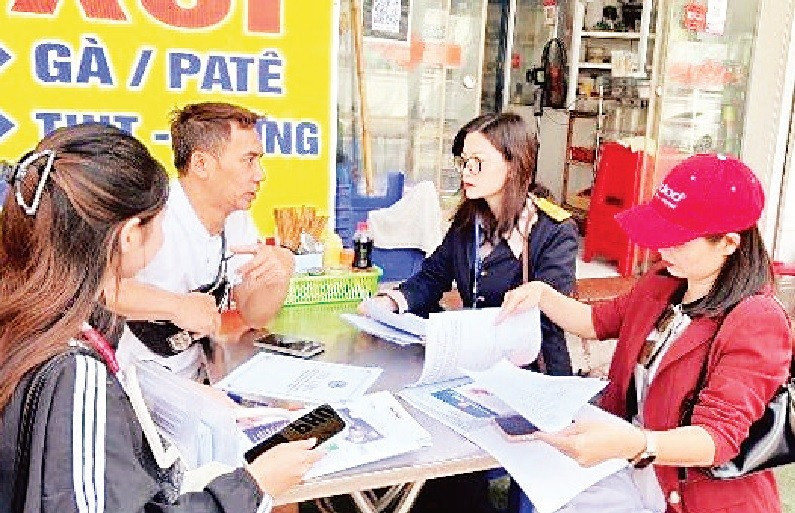 Cán bộ ngành Thuế Hà Nội phát tờ rơi và phiếu khảo sát, tuyên truyền chủ trương đến hộ kinh doanh tại phường Yên Hòa.