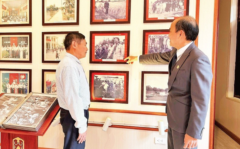 Ông Phùng Văn Tiệp (bên phải), Trưởng phòng Văn hóa-Xã hội xã Dân Hòa giới thiệu cho khách tham quan các hình ảnh về Chủ tịch Hồ Chí Minh tại Nhà lưu niệm Chủ tịch Hồ Chí Minh tại xã Dân Hòa.