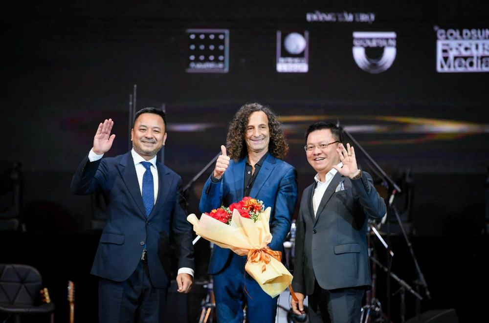 Ông Lê Quốc Minh, Tổng biên tập Báo Nhân Dân (phải); Ông Nguyễn Thùy Dương, Chủ tịch IB Group Việt Nam (trái) cùng Huyền thoại Saxophone Kenny G tại Live concert "Kenny G Live in Vietnam" - nằm trong dự án âm nhạc quốc tế vì cộng đồng Good Morning Vietnam ib2.png