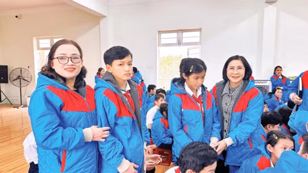 Bà Nguyễn Thị Thu Hà (người ngoài cùng, bên phải, hàng đứng) mặc áo ấm cho học sinh ở Trung tâm Nuôi dạy trẻ khuyết tật Võ Hồng Sơn.
