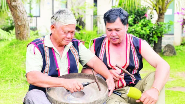 Nghệ nhân Ưu tú Đinh Dôch (bên trái) hướng dẫn kỹ thuật chỉnh chiêng cho học viên. (Ảnh LAM NGUYÊN)