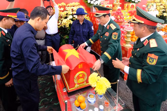 Các đại biểu thực hiện nghi lễ phủ cờ Tổ quốc lên hài cốt liệt sĩ vừa quy tập tại xã Minh Đức, thành phố Đồng Nai.