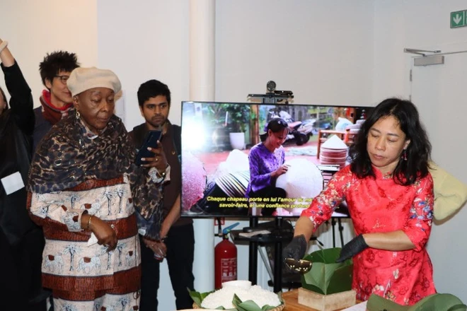 Chị Nguyễn Thị Liên, Việt kiều tại Brussels, giới thiệu cách gói bánh chưng. (Ảnh: HƯƠNG GIANG/TTXVN)