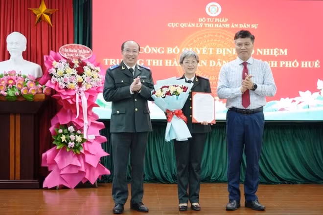 Cục trưởng Cục Quản lý Thi hành án dân sự Nguyễn Thắng Lợi và Trưởng Ban Tổ chức Thành ủy Huế Phan Xuân Toàn trao quyết định, tặng hoa chúc mừng bà Phan Thùy Dương.