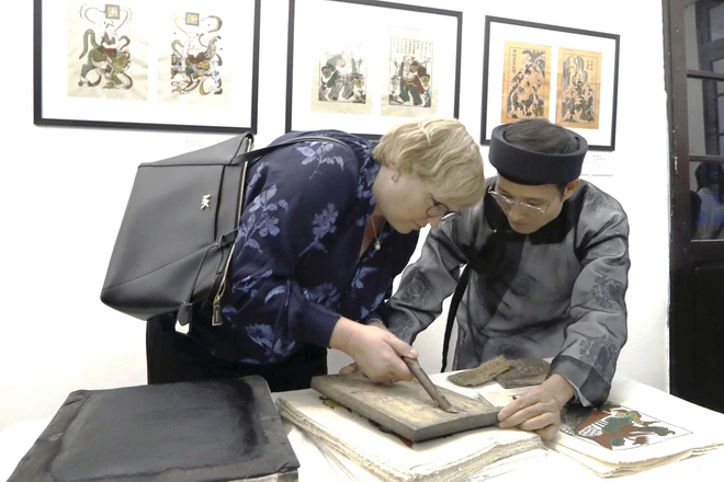 Nghệ nhân Nguyễn Hữu Quả giới thiệu kỹ thuật in tranh Đông Hồ tới du khách quốc tế, tại Bảo tàng Mỹ thuật Việt Nam.