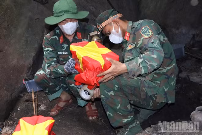 Những hài cốt liệt sĩ được bộ đội cẩn trọng phủ cờ Tổ quốc, đưa ra khỏi hang sâu.