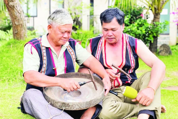 Nghệ nhân Ưu tú Đinh Dôch (bên trái) hướng dẫn kỹ thuật chỉnh chiêng cho học viên. (Ảnh LAM NGUYÊN)