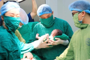 Giáo sư, Tiến sĩ Nguyễn Duy Ánh, Giám đốc Bệnh viện Phụ sản Trung ương thực hiện cắt dây rốn chậm cho em bé. 