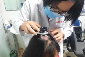 Bác sĩ kiểm tra tình trạng rụng tóc của bệnh nhân.