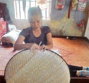 Bên chiếc giường gỗ mộc, chị Liên đang hằng ngày đan nong.