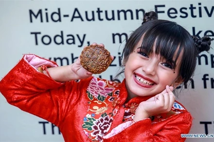 Bé gái chụp ảnh cùng chiếc bánh Trung thu tại trung tâm thương mại ở Manila, Philippines, ngày 11-9. (Ảnh: Tân Hoa xã)