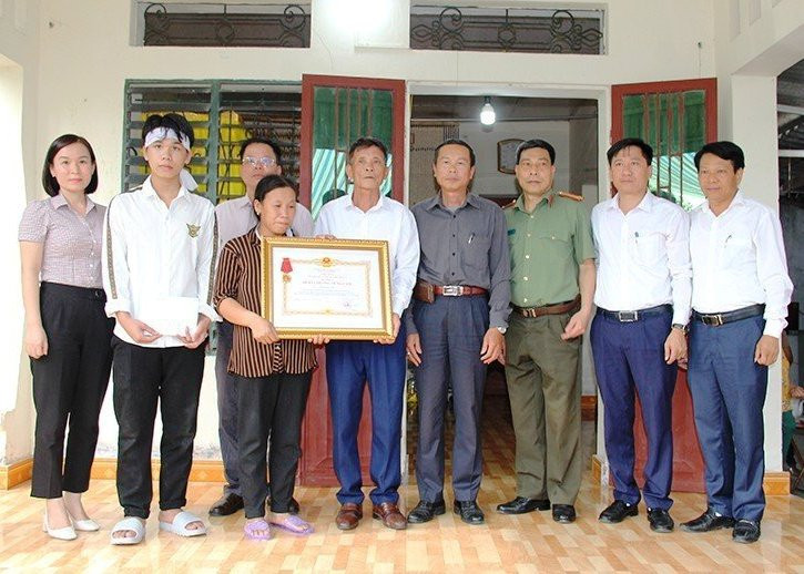 Đại diện đoàn công tác trao Huân chương Dũng cảm cho người thân anh Phạm Ngọc Anh.