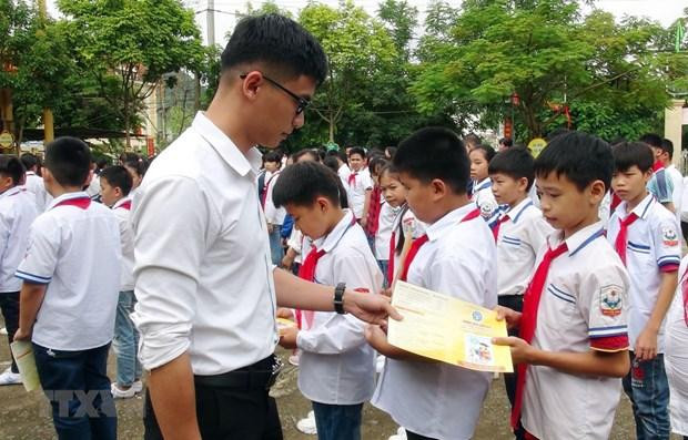 Cán bộ bảo hiểm phát tờ rơi tuyên truyền về bảo hiểm y tế học sinh. (Ảnh: TTXVN)
