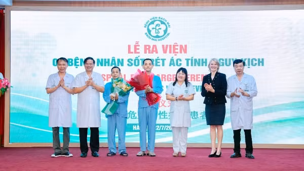Hai bệnh nhân nhận hoa chúc mừng của thầy thuốc trước khi ra viện.
