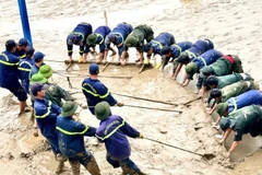 Các đồng chí công an tỉnh Quảng Trị hợp sức cào bùn ở sân trường tại thành phố Huế. (Ảnh: VGP)