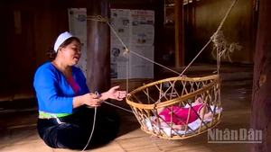 Người mẹ Mường dịu dàng ru con ngủ bên chiếc nôi tre.