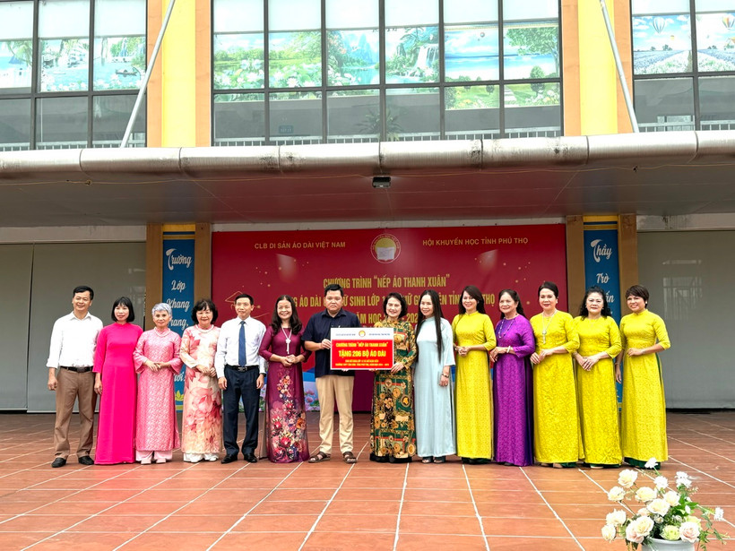 Đại diện Câu lạc bộ Di sản áo dài Việt Nam trao biểu trưng 206 bộ áo dài cho Trường Phổ thông trung học huyện Tân Sơn. (Ảnh: Ban tổ chức)