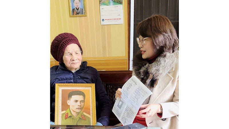 Tình nguyện viên Nguyễn Thanh Thủy trao tặng ảnh và bản chụp kỷ vật của liệt sĩ Trần Đức Ngạn cho thân nhân.