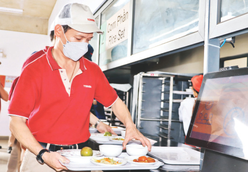 Công nhân Công ty TNHH Sản phẩm công nghiệp Toshiba Asia lấy khẩu phần ăn tại nhà hàng.