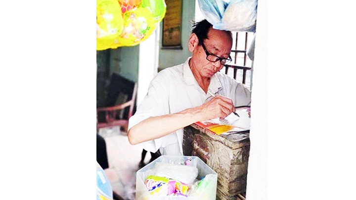 Nhà văn Trần Văn Thước đứng viết văn. Ảnh: VŨ ĐẢM