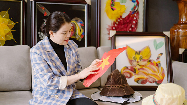 Chị Sinh bên tác phẩm tranh làm từ lá cây khô.