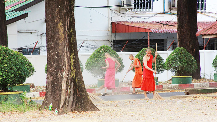Các nhà sư trẻ quét chùa trong buổi sớm ở Thủ đô Vientiane.