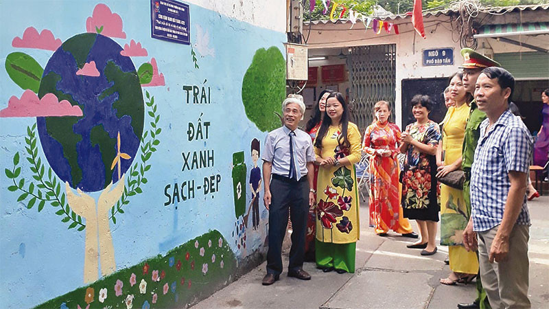 Ông Nguyễn Hữu Bằng (bên trái) cùng người dân Khu dân cư số 3 bên công trình tranh bích họa, làm đẹp diện mạo khu phố.