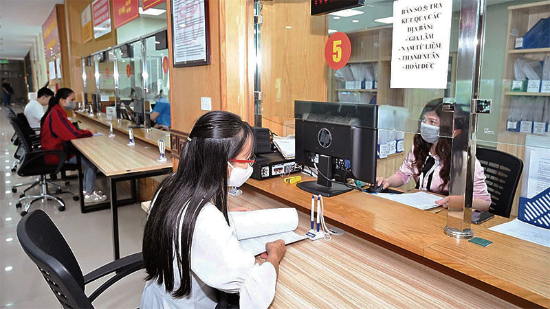 Cán bộ tại bộ phận một cửa của Sở Kế hoạch và Đầu tư Hà Nội hướng dẫn, hỗ trợ doanh nghiệp thực hiện thủ tục hành chính. (Ảnh: MINH HÀ)