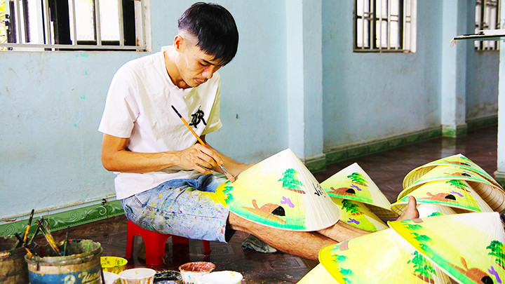 Anh Nhật đang vẽ phong cảnh quê hương lên chiếc nón.