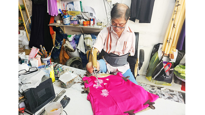 Họa sĩ Trần Hùng Bảo vẽ tranh trên áo dài.