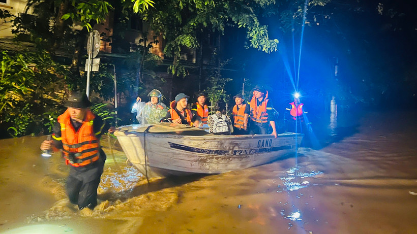 Lực lượng công an dùng thuyền vượt nước lũ cứu dân. (Ảnh: THANH SƠN)