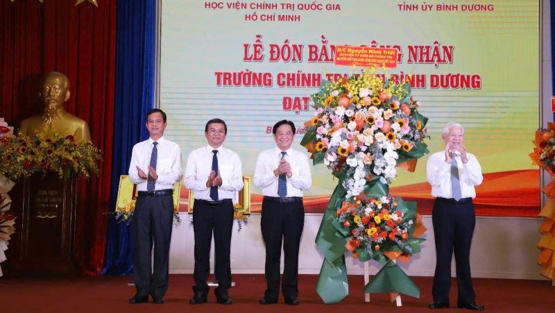 Nguyên Chủ tịch nước Nguyễn Minh Triết (bên phải) trao tặng lẵng hoa chúc mừng Trường Chính trị tỉnh Bình Dương đạt chuẩn mức 1. 