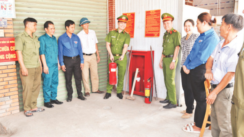 Đại úy Mai Hùng Hiếu (người cầm bình chữa cháy) hướng dẫn người dân cách sử dụng hiệu quả bình chữa cháy.