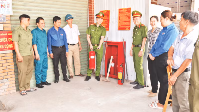 Đại úy Mai Hùng Hiếu (người cầm bình chữa cháy) hướng dẫn người dân cách sử dụng hiệu quả bình chữa cháy.