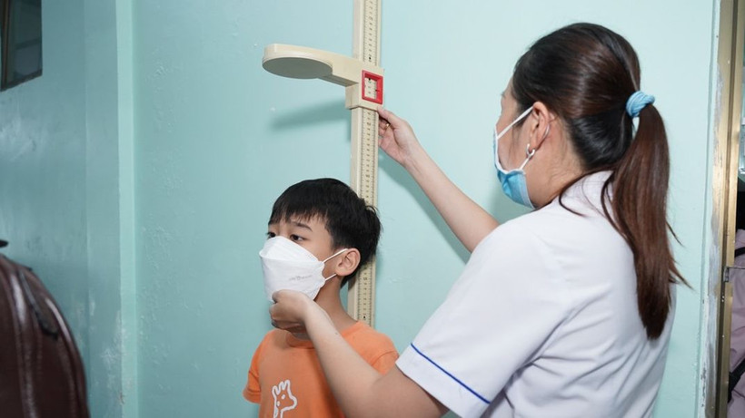 Nhân viên y tế đo chiều cao cho trẻ khi tham gia tầm soát.