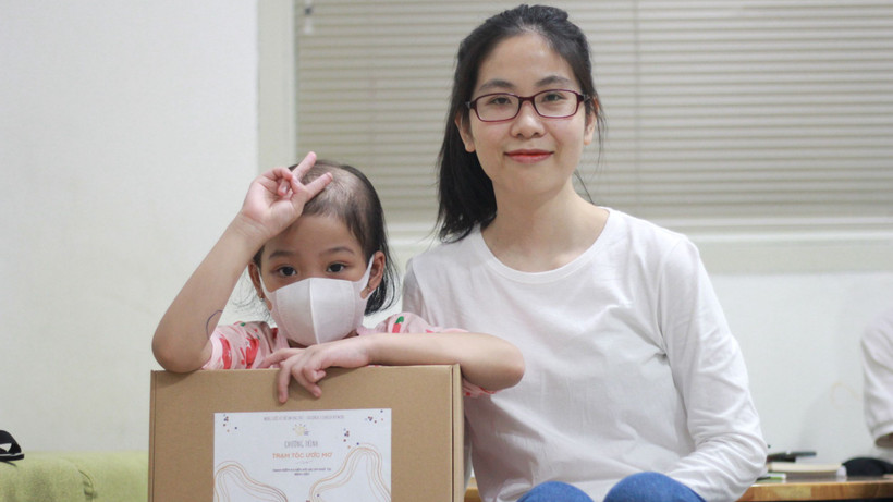 Diệu Thuần và một bé gái nhận được bộ tóc mới. 