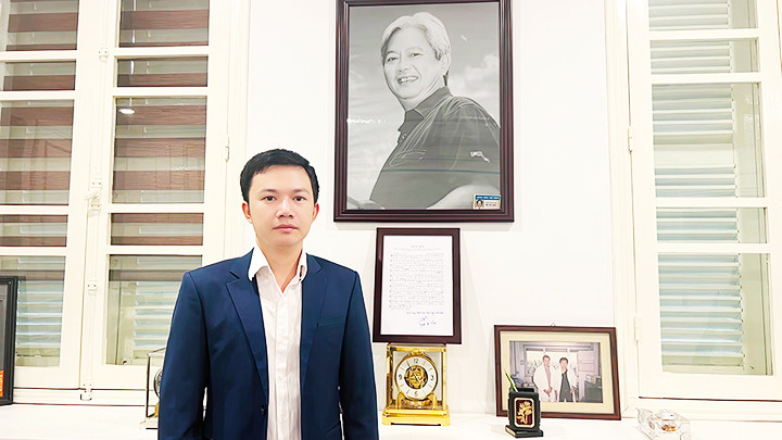 Nhạc sĩ Nguyễn Bá Hùng tại phòng truyền thống Bệnh viện Hữu nghị Việt Đức, phía sau là tấm ảnh thầy Tôn Thất Bách và bài hát “Thầy tôi”.