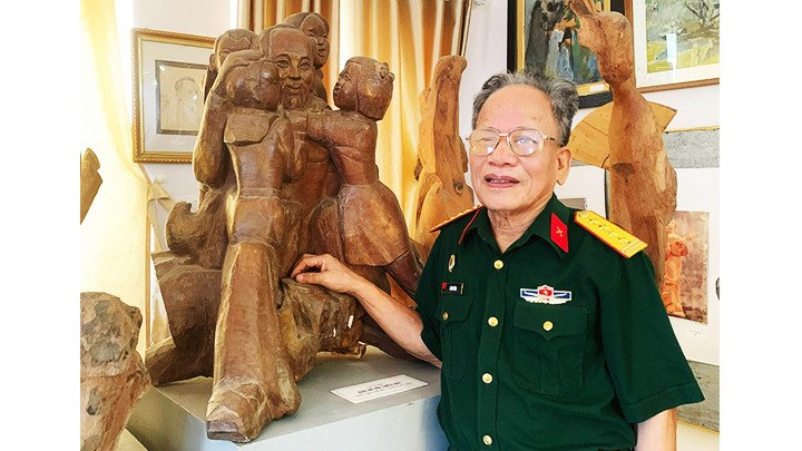 Họa sĩ Lê Duy Ứng bên tác phẩm tượng Bác Hồ với các cháu thiếu nhi.