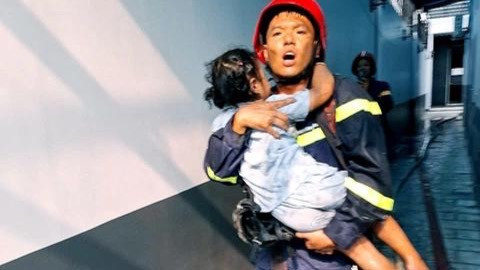Lực lượng cứu hộ bế một em bé ra ngoài hiện trường vụ cháy.