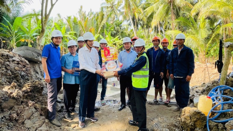 Thành viên Hội đồng thành viên EVNSPC Lê Xuân Hải (áo trắng) tặng quà động viên lực lượng lao động thi công dự án trên địa bàn tỉnh Bến Tre ngày 26 Tết.