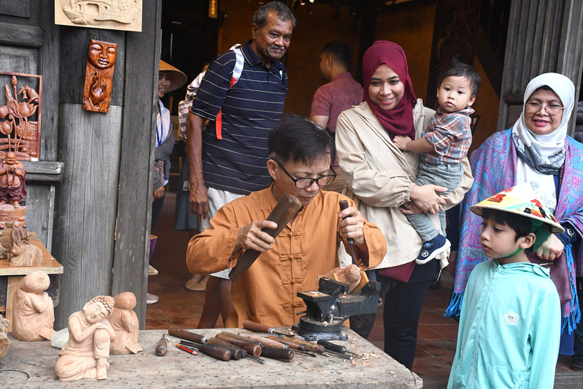 Khách du lịch tham quan các sản phẩm của làng mộc Kim Bồng.