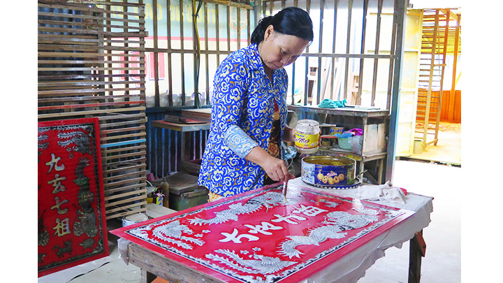 Công đoạn tô keo cho tranh kim tuyến nhũ vàng.