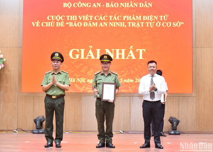 Các đồng chí Ủy viên Trung ương Đảng: Thượng tướng Trần Quốc Tỏ, Phó Bí thư Đảng ủy Công an Trung ương, Thứ trưởng điều hành hoạt động của Bộ Công an, Trưởng Ban Tổ chức cuộc thi; Lê Quốc Minh, Tổng Biên tập Báo Nhân Dân, Phó Trưởng Ban Tuyên giáo Trung ương, Chủ tịch Hội Nhà báo Việt Nam trao giải Nhất cho tác giả tại Lễ tổng kết. (Ảnh: THỦY NGUYÊN)